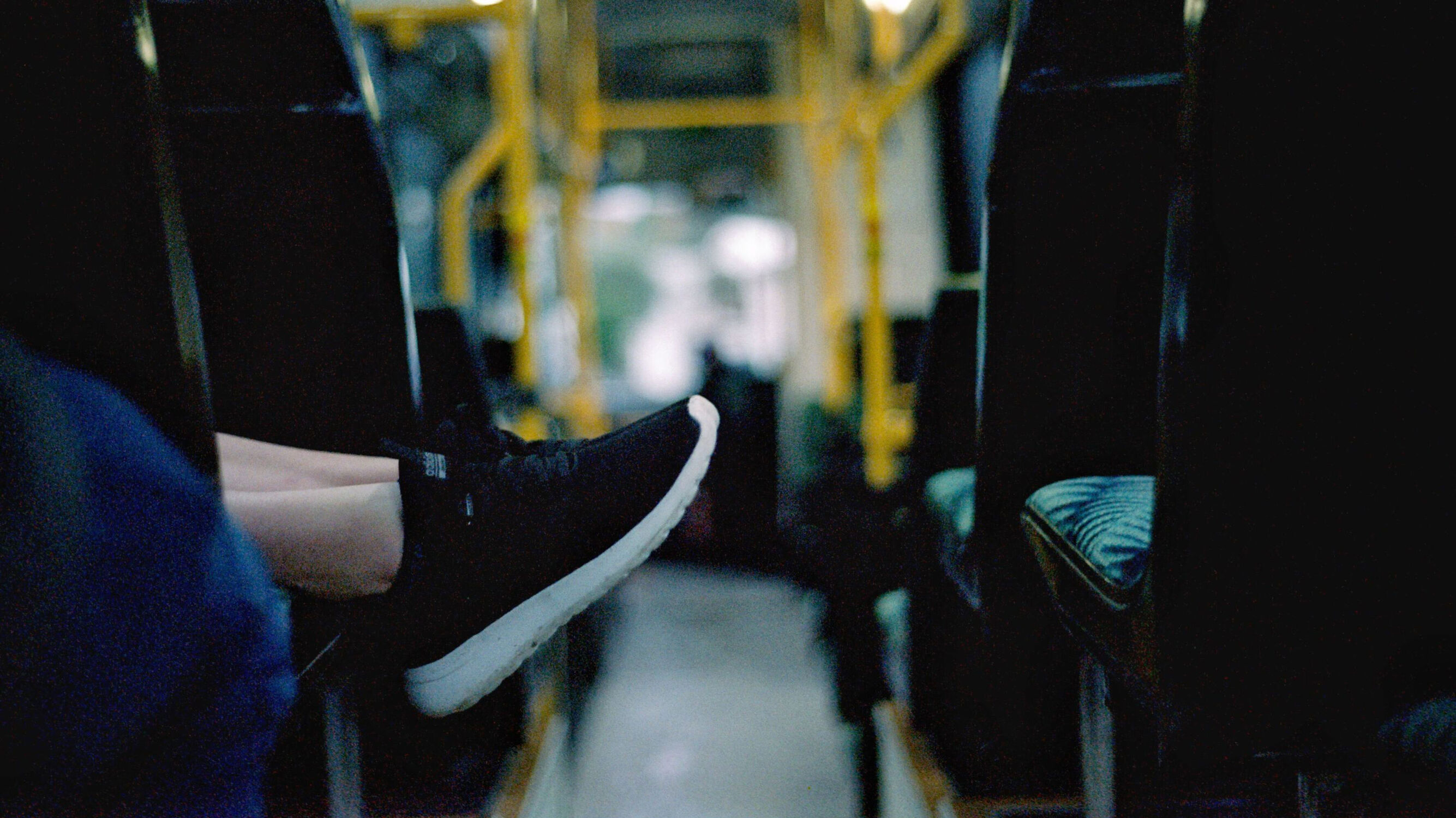 Feet hanging over the edge of a seat in a bus