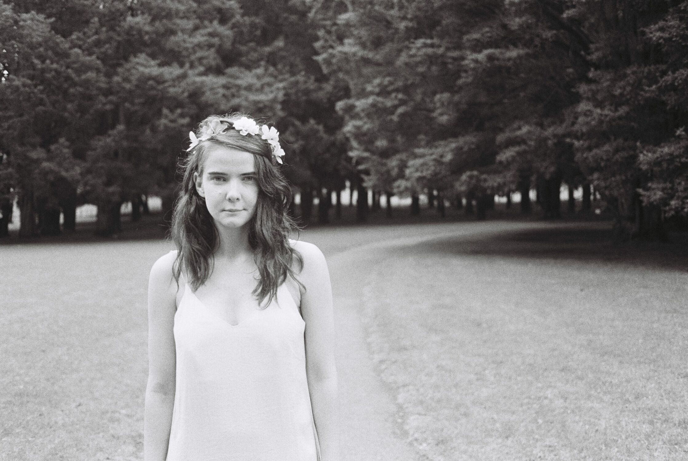 A woman standing in front of a path, trees and grass