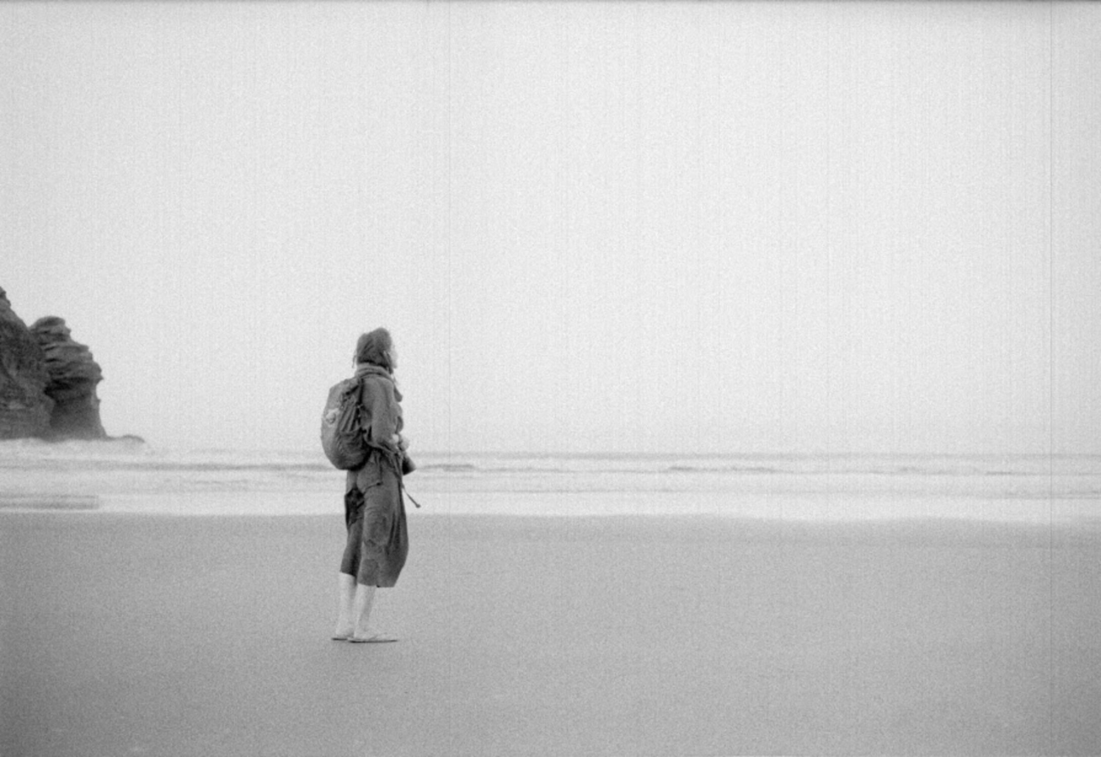 A scan of a girl on a beach, kind of grainy with strong vertical scan lines in the image